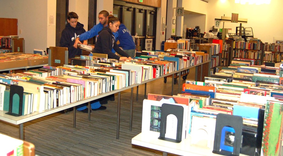 EOP students arrange used books on long tables for the Friends of the Library Used Book Sale